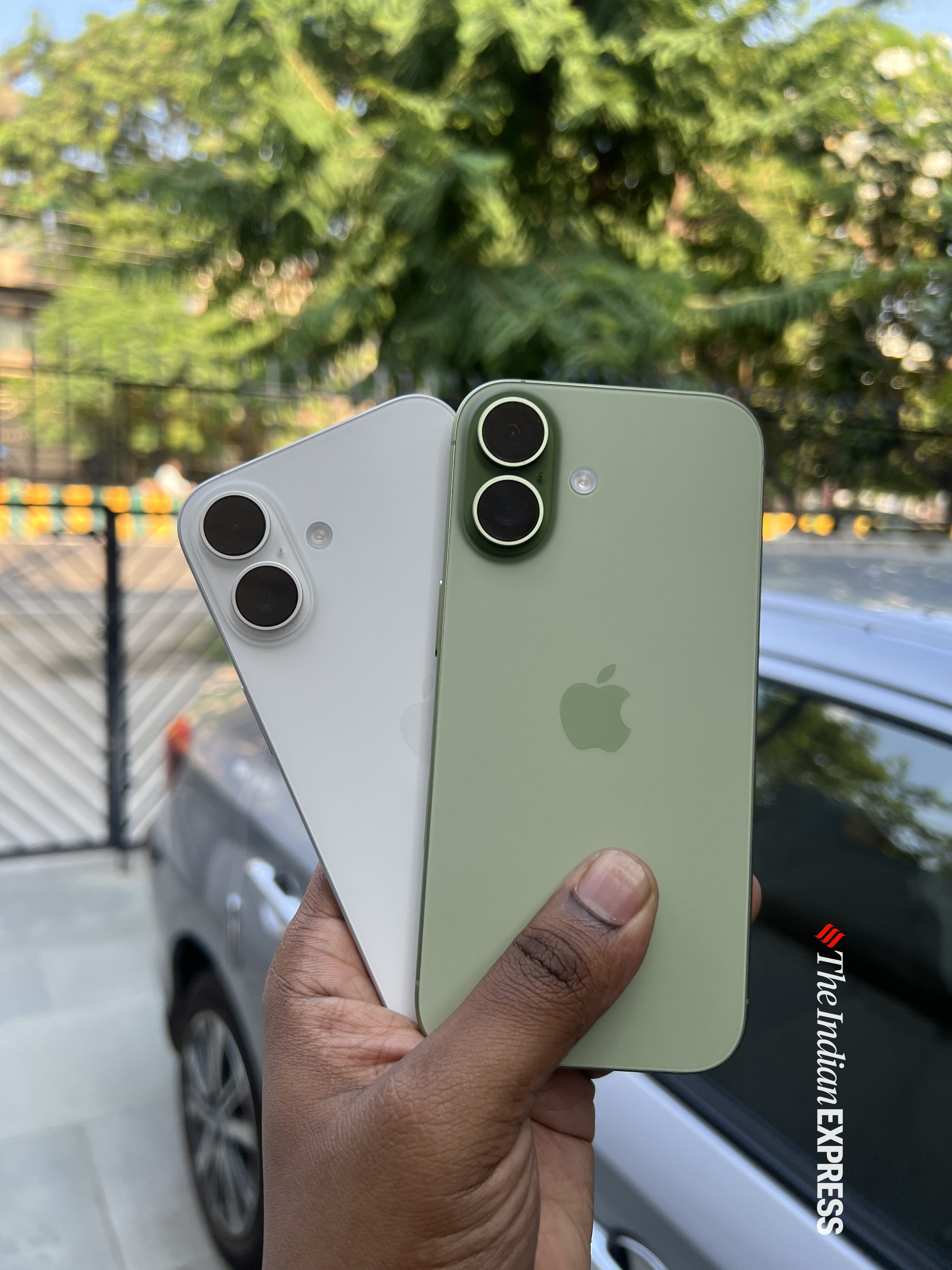 Sage-green iPhone 17 (right) next to the white iPhone 16 (left), showing how closely the new model mirrors last year’s minimalist design. (Image: Bijin Jose/The Indian Express)