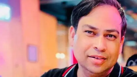 Jannatul Mauwa Raish Ahmed, a man with dark hair and wearing a black polo shirt top with red and white stripes on the collar