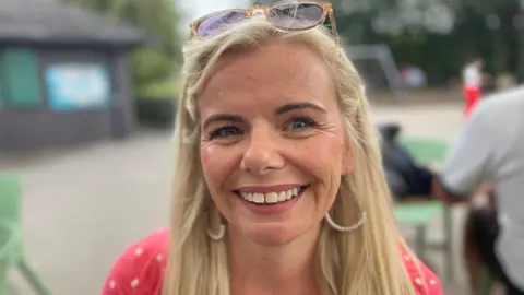 Gemma is smiling and has spectacles resting on top of her head