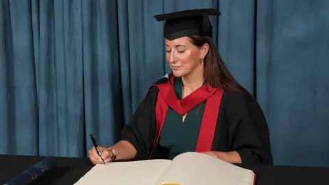Supplied Dr Bennett is wearing graduation robes and a mortar board