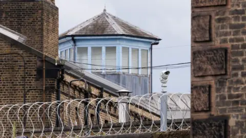 Getty Images A security camera and barbed wire outside HMP Wandsworth prison in London. 