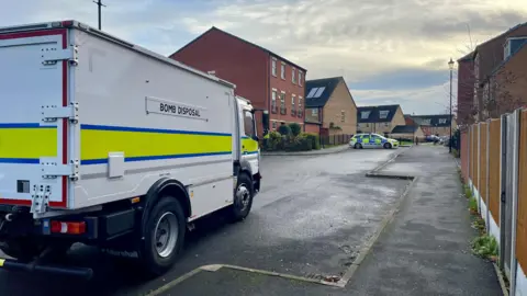 BBC A bomb disposal lorry with a police car in the background