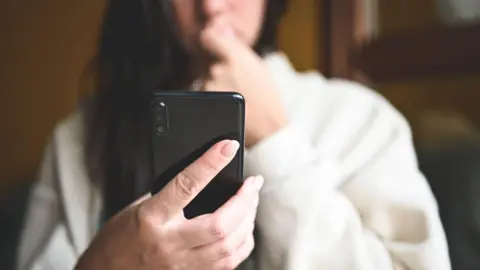 Getty Images A woman looking at her phone 
