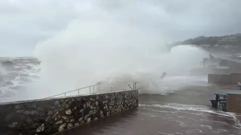 BBC/Johnny Rutherford Waves crashing over Teignmouth promenade in Devon. 